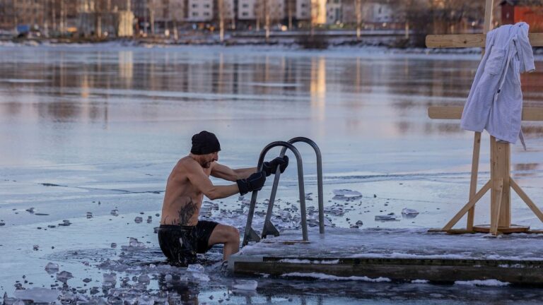 Mies nousee avantouinnista jäisessä järvessä pyyhe odottamassa